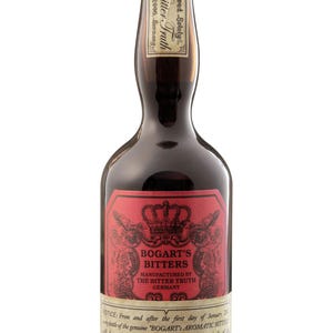 May include: A dark brown glass bottle of Bogart's Bitters with a gold cap. The main label is red with a black crown graphic and text reading Bogart's Bitters Manufactured by The Bitter Truth Germany. A cream-colored secondary label is below.