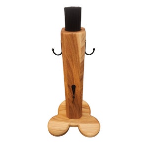 May include: Wooden brush holder with a black brush and three hooks. The holder has a three-pronged base.