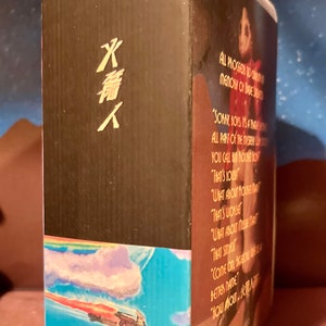 May include: A VHS tape with a black background and a rainbow and blue sky with a flying figure. The text on the tape reads "ALL PROCEEDS TO CREATE A MEMORY OF DAVE STREET" and "SORRY, BOYS, IT'S A TRAGEDY. ALL PART OF THE NORTHERN LIGHTS. YOU CALL HIM NONE OTHER THAN... THAT'S LOW. WHAT ABOUT ROCKET MAN? THAT'S WORSE. WHAT ABOUT MIKE THAT? THAT STINKS. COME ON, BACK ON THE... BETTER NAME. HOW ABOUT..."