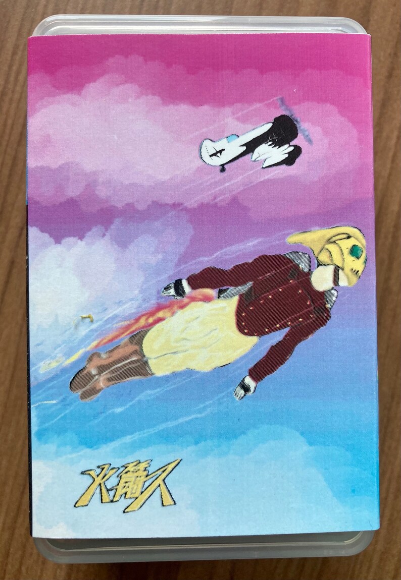 May include: A yellow and red illustration of a person flying through the air with a jetpack. The background is a pink and blue watercolor sky with a small white airplane flying in the distance. The text "火龍" is written in yellow at the bottom of the image.