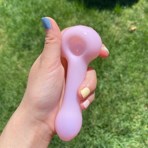 May include: A light purple glass pipe with a rounded bowl and a long, slender stem.