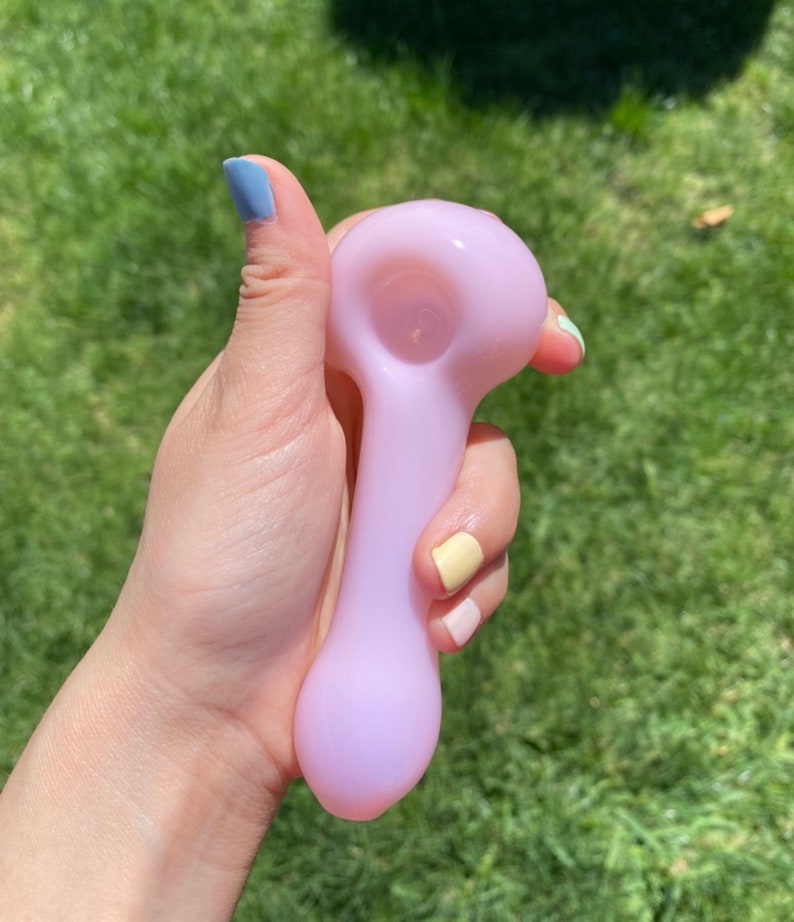 May include: A light purple glass pipe with a rounded bowl and a long, slender stem.