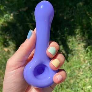 May include: A purple glass pipe with a rounded bowl and a long, slender stem.