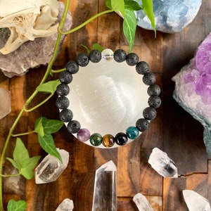 Op de afbeelding: Een zwarte lava armband met een verscheidenheid aan gekleurde edelsteen kralen, waaronder amethist, groene aventurijn, tijgeroog en blauwe apatiet.