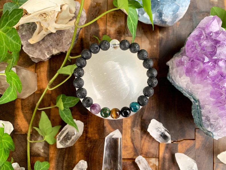 Op de afbeelding: Een zwarte lava armband met een verscheidenheid aan gekleurde edelsteen kralen, waaronder amethist, groene aventurijn, tijgeroog en blauwe apatiet.