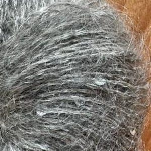 May include: Close-up of a ball of gray yarn with a textured, slightly fuzzy appearance. The yarn appears to be a blend of gray and white fibers, creating a heathered effect. The fibers are tightly wound, and the overall texture is soft and inviting.