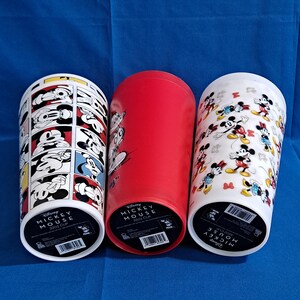 Puede incluir: Tres vasos de Disney Mickey Mouse de 946 ml. Uno presenta un dise&ntilde;o de c&oacute;mic, otro es rojo liso y el tercero tiene un patr&oacute;n de Mickey y Minnie Mouse. Los vasos son cil&iacute;ndricos y tienen una base blanca con informaci&oacute;n del producto.