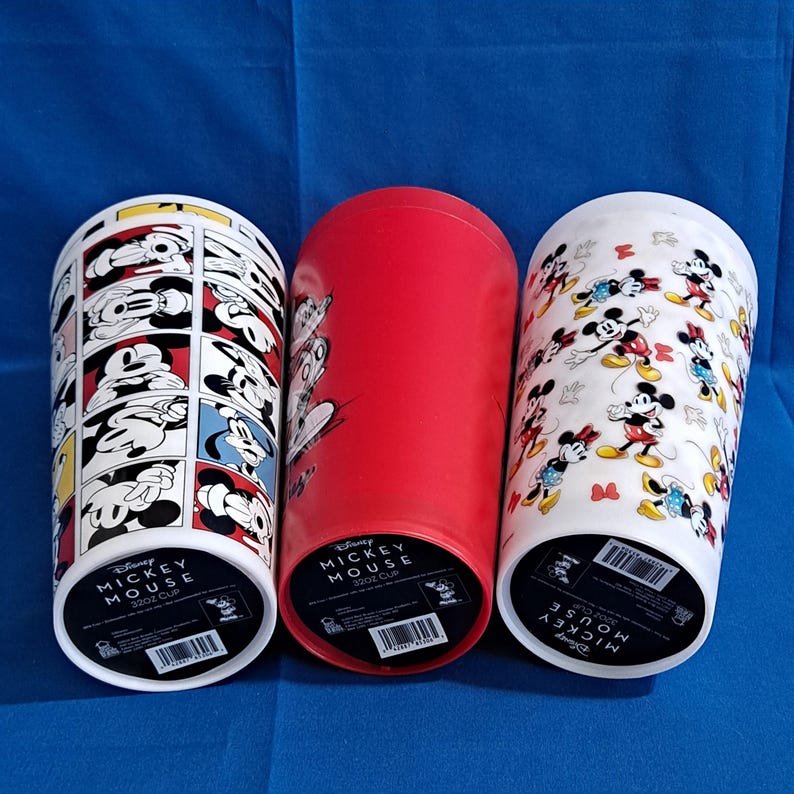 Puede incluir: Tres vasos de Disney Mickey Mouse de 946 ml. Uno presenta un dise&ntilde;o de c&oacute;mic, otro es rojo liso y el tercero tiene un patr&oacute;n de Mickey y Minnie Mouse. Los vasos son cil&iacute;ndricos y tienen una base blanca con informaci&oacute;n del producto.