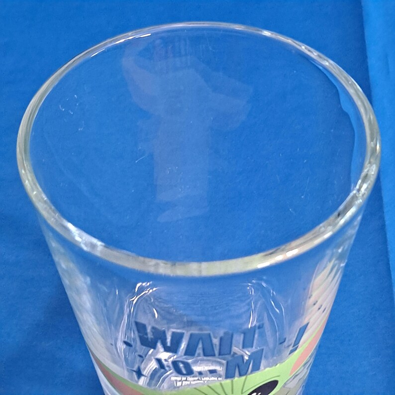Peut inclure: Verre &agrave; boire en verre transparent avec les mots "Wait for Me!" en bleu et vert. Le verre a une large ouverture et une forme l&eacute;g&egrave;rement conique. Le verre est sur un fond bleu.