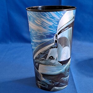 May include: Tall plastic tumbler with a black rim and a blue and white graphic of a character's helmet from a science fiction series. The tumbler has a cylindrical shape and is set against a blue background.