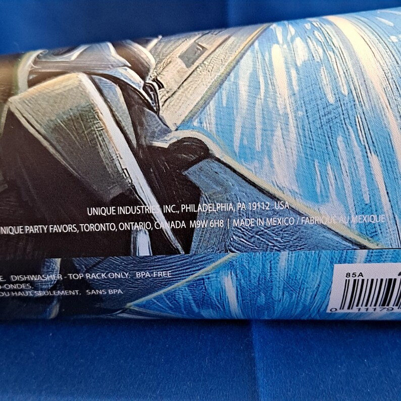 May include: A rolled-up, blue and white party favor product with text including the manufacturer's name and address. The product is BPA-free and top-rack dishwasher safe.