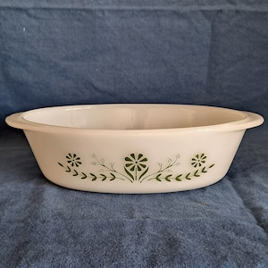 May include: White oval baking dish with a green floral design. The design features three stylized flowers with leaves and stems.