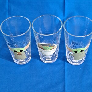 Peut inclure: Trois verres transparents avec des images de Grogu, &eacute;galement connu sous le nom de Baby Yoda, de The Mandalorian. Chaque verre pr&eacute;sente un design Grogu diff&eacute;rent et les mots "NOM", "WAIT" et "490" imprim&eacute;s.