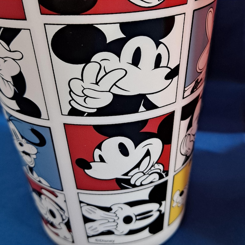 Puede incluir: Taza de cer&aacute;mica blanca con un dise&ntilde;o de c&oacute;mic que presenta a Mickey Mouse en varias poses. Los paneles tienen fondos rojos, negros, blancos, azules y amarillos. La taza tiene un acabado brillante y una forma cil&iacute;ndrica cl&aacute;sica.