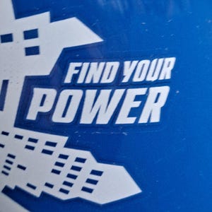 May include: Close-up of a blue surface with white graphic elements and the text "FIND YOUR POWER". The design features geometric shapes and bold lettering, creating a modern aesthetic.