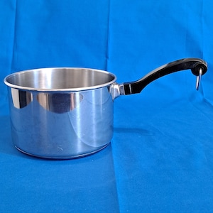 May include: A stainless steel saucepan with a black handle and a silver hanging loop. The pot has a shiny, reflective surface and is set against a blue background. This kitchenware is designed for cooking.