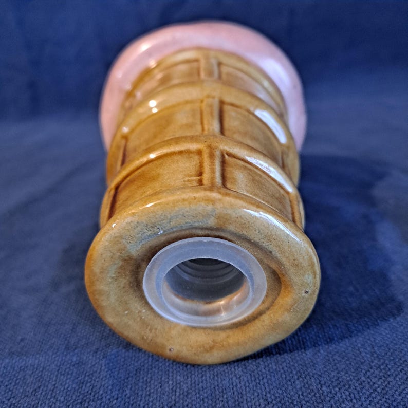 K&ouml;nnte beinhalten: Ein salzstreuer aus Keramik in Form einer Eist&uuml;te. Der Kegel ist braun mit einem Waffelmuster, und das Eis ist rosa. Der Streuer hat einen transparenten Kunststoffring um die &Ouml;ffnung.