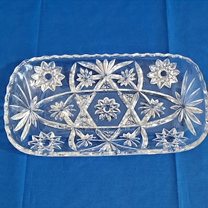 Puede incluir: Una taza de cerámica blanca con un asa negra y el texto "But First, Coffee" en negro, con una fuente de estilo manuscrito. La taza está sobre una superficie blanca.