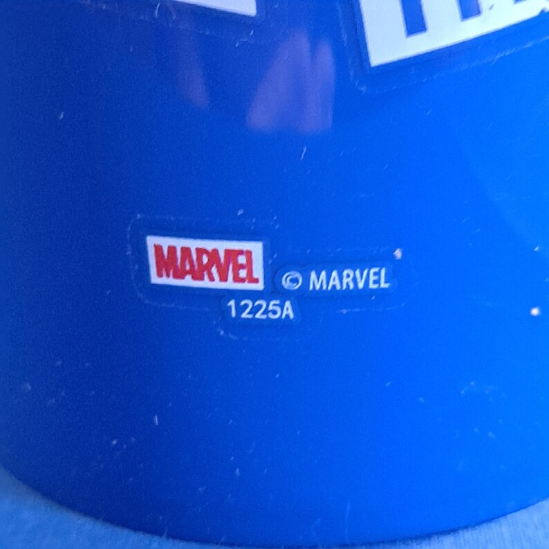 May include: Close-up of a blue object with the Marvel logo in a white rectangle. The word "MARVEL" is in red and white. Below the logo is the text "1225A" and the copyright symbol and the word "MARVEL".