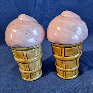 K&ouml;nnte beinhalten: Ein Paar Salz- und Pfefferstreuer aus Keramik in Form von Eiswaffeln. Die Eisportionen sind hellrosa mit dunkleren Sprenkeln, und die Waffeln sind hellbraun mit einem Waffelmuster.