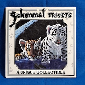 May include: Square trivet with two tiger cubs, one orange and black, the other white and black. The trivet has the text "Schimmel TRIVETS" and "A UNIQUE COLLECTIBLE" on a cream background with paw prints.