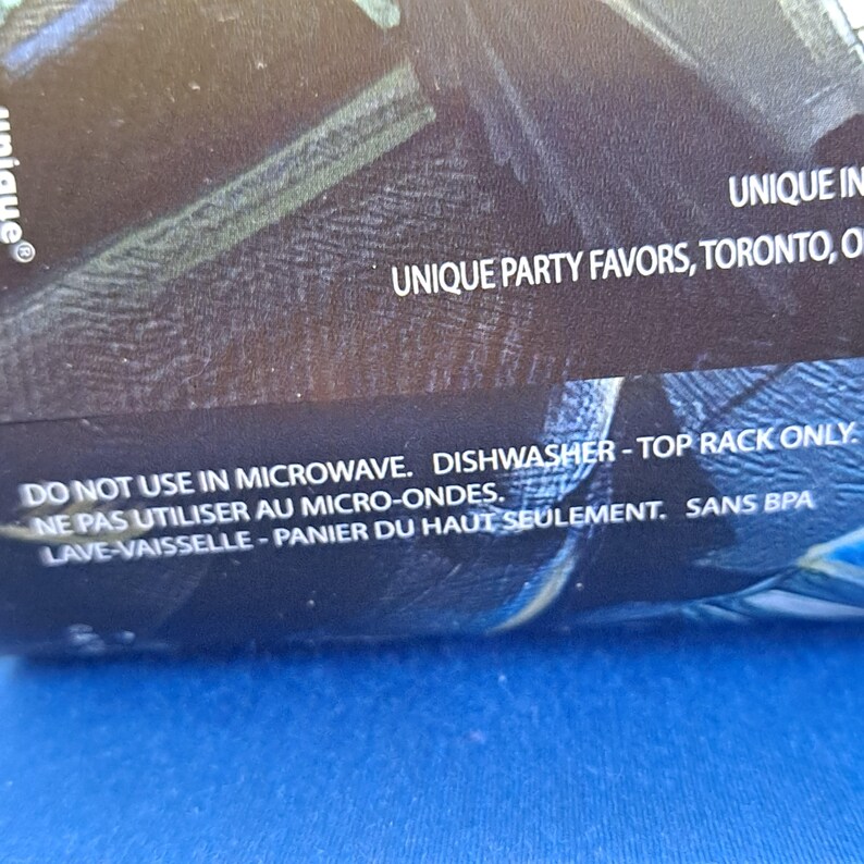 May include: Close-up of a product label with the text "UNIQUE PARTY FAVORS, TORONTO, O". The label also includes the instructions "DO NOT USE IN MICROWAVE. DISHWASHER - TOP RACK ONLY."