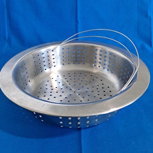 May include: A stainless steel colander with a perforated bowl and a wire handle. The colander is round with a wide rim and numerous small holes for draining. The handle arches over the top.