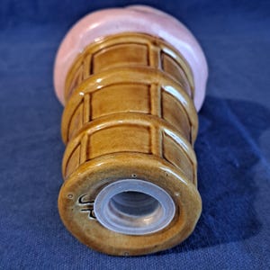 K&ouml;nnte beinhalten: Ein salzstreuer aus Keramik in Form einer Eist&uuml;te. Der Kegel ist braun mit Waffelmuster, und das Eis ist rosa. Der Boden hat einen transparenten Kunststoffstopfen. Ein skurriles K&uuml;chen- oder Esszimmer-Accessoire.