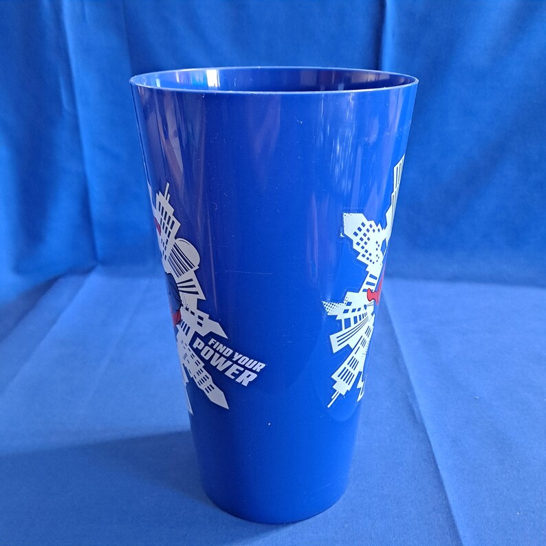 May include: A tall, blue plastic tumbler with a white graphic design and the words "FIND YOUR POWER" printed on the side. The tumbler is empty and sits against a blue background.