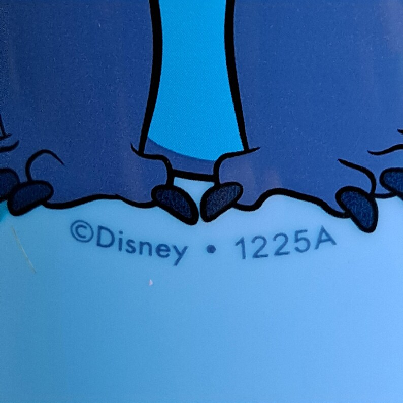 May include: Close-up of a light blue surface with a dark blue cartoon character design. The text "&copy;Disney &bull; 1225A" is printed in white. The design features a character's feet and lower body.
