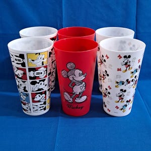 Puede incluir: Seis vasos de pl&aacute;stico con dise&ntilde;os de Mickey Mouse. Dos vasos rojos con un gr&aacute;fico de Mickey Mouse y la palabra "Mickey". Dos vasos blancos con gr&aacute;ficos de Mickey Mouse y Minnie Mouse. Dos vasos blancos con paneles de c&oacute;mic de Mickey Mouse.