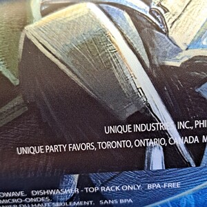 May include: Close-up of a product package with the text "UNIQUE INDUSTRIES INC., PHI" and "UNIQUE PARTY FAVORS, TORONTO, ONTARIO, CANADA M". The package is blue and gray.
