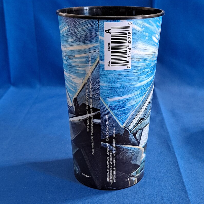 May include: A tall, cylindrical plastic cup with a black rim and a blue and white graphic design. The cup has a barcode and text that reads "DO NOT USE IN MICROWAVE DISHWASHER TOP RACK ONLY BPA FREE".