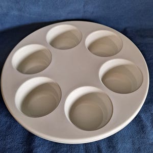 以下が含まれることがあります： 6つの円形のくぼみのある白いプラスチック製の丸いトレイ。ジュエリーやクラフト用品などの小さなアイテムを収納するのに最適です。