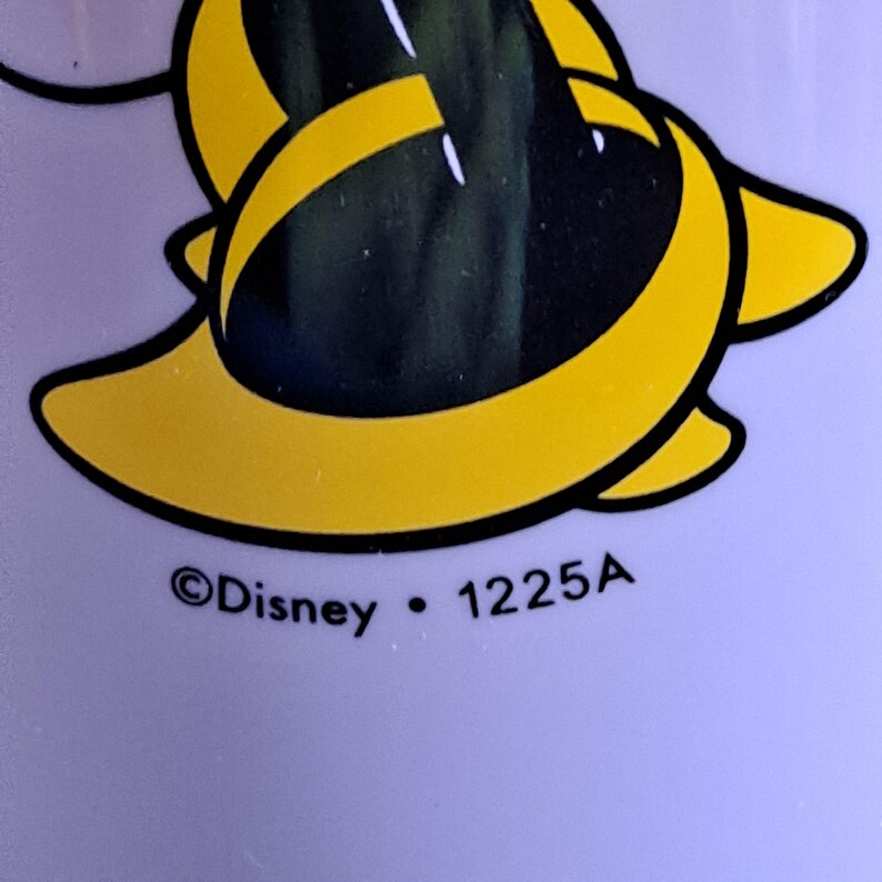 May include: Close-up of a yellow and black cartoon character design on a light purple background. The text "&copy;Disney &bull; 1225A" is printed below the design.