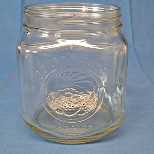 Puede incluir: Un tarro de vidrio transparente con un logotipo redondo en relieve que dice "John Mason" y "Canister".