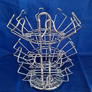 May include: A chrome metal coffee pod holder with three tiers and a circular base. The holder has a capacity of 36 pods.