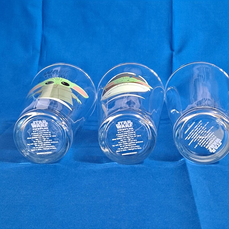 Peut inclure: Trois verres transparents repr&eacute;sentant des personnages de Star Wars. Chaque verre a un design diff&eacute;rent, dont le personnage Grogu. Les verres ont le logo Star Wars et du texte en bas.