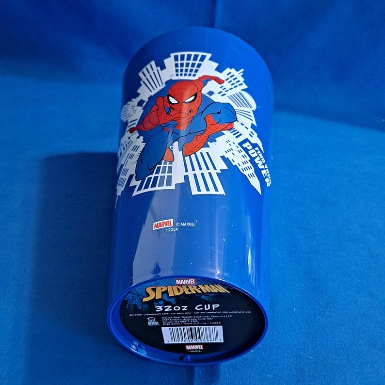 May include: A blue 32oz cup featuring Spider-Man in a dynamic pose, with a cityscape design. The cup has the Marvel logo and the words "Spider-Man" and "32oz CUP" printed on it.