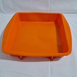 Może przedstawiać: Pomarańczowa silikonowa forma do pieczenia o kwadratowym kształcie. Forma wykonana jest z elastycznego silikonu i ma gładką, nieprzywierającą powierzchnię.