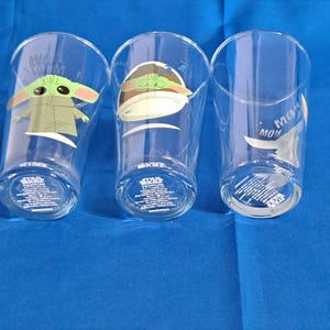 Peut inclure: Trois verres transparents avec des images de Grogu de The Mandalorian. Un verre a Grogu avec le texte "WANT TO M". Un autre verre a Grogu dans un pod. Le troisi&egrave;me verre a le texte "MOM" et Grogu. Chaque verre a du texte Star Wars en bas.