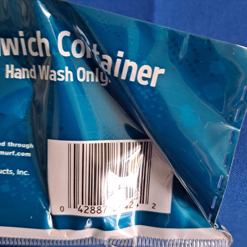 May include: A close-up of a blue sandwich container package with the words "Sandwich Container" and "Hand Wash Only" printed in white. A barcode is visible near the bottom of the package.