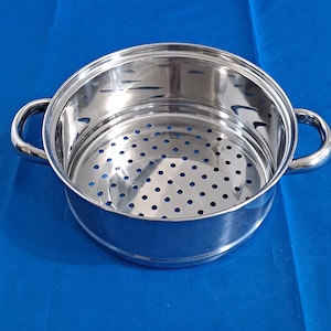 May include: A round, polished stainless steel steamer insert featuring a perforated base and sides for efficient steam circulation. The cooking vessel includes two sturdy, curved side handles for easy lifting and a smooth, reflective metallic finish.