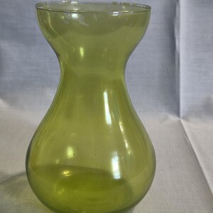 May include: A translucent lime green glass vase with a rounded, bulbous base that tapers into a narrow neck before widening at the top rim. The glass has a smooth, polished finish and a consistent light green hue throughout the entire structure.