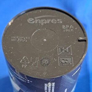 May include: A close-up of a black plastic lid with the embossed text "enpres" and "BPA FREE". The lid also features the text "HECHO EN MEXICO" and several recycling symbols. The lid is for a container.