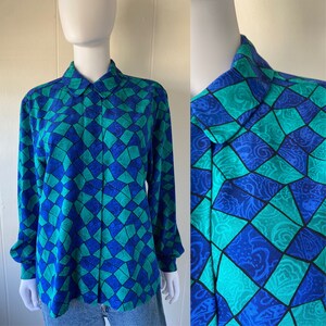 May include: A long-sleeved button-up shirt with a geometric pattern in shades of blue and green. The shirt has a collar and a button-up front.