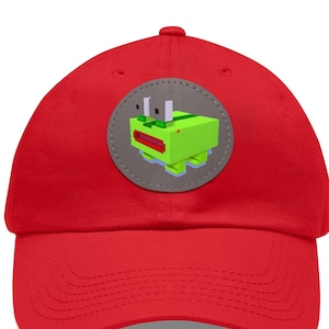 Può includere: Un berretto da baseball rosso brillante con un design a rana verde pixelato su una toppa grigia. La rana ha occhi bianchi e bocca rossa. Il berretto è realizzato in materiale morbido e ha una visiera curva.