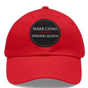 Może przedstawiać: Czerwona czapka bejsbolówka z czarną naszywką z napisem "MAKE LYING WRONG AGAIN" i pięcioma czerwonymi gwiazdami.