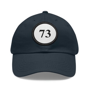 May include: A navy blue baseball cap with a white circle patch featuring the number 73 in black.