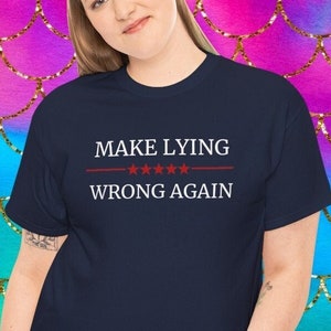 May include: A navy blue t-shirt with the text "MAKE LYING WRONG AGAIN" in red lettering with five red stars above the word "AGAIN".
